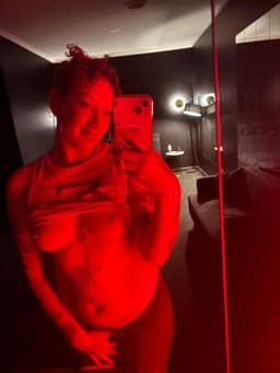 Azara Sin taking a red-lit mirror selfie in a private indoor setting during a sensual, tantra-inspired moment in Melbourne