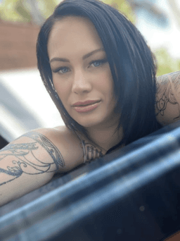 Lexi Love independent erotic massage provider with dark hair and arm tattoos, featured profile image taken outdoors in natural light.