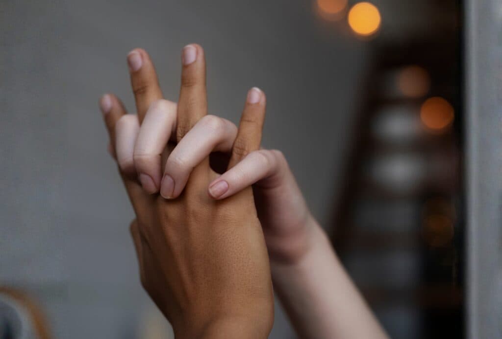 A close-up of hands gently touching, highlighting the intimacy and connection found in the benefits of Tantric Massage.